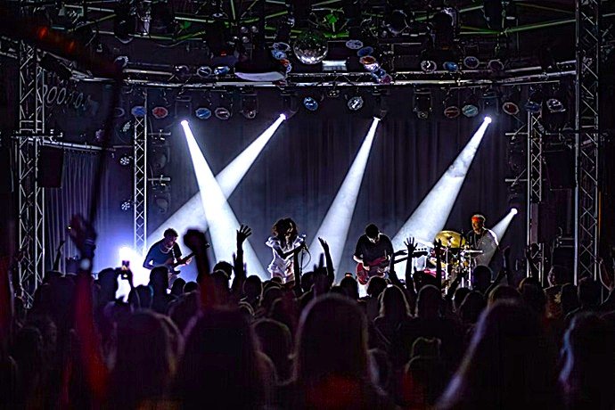 Especialistas audiovisuales monitorizando la señal acústica y lumínica en una torre técnica durante un concierto de rock.